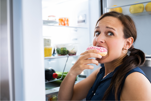 woman over 40 eating emotionally eating from refrigerator 