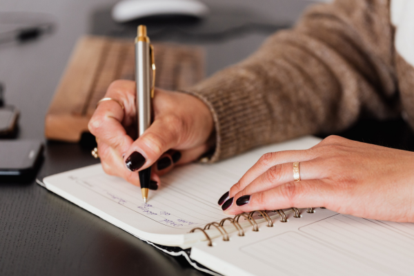 Person writing in a notebook to track food, lifestyle, and weight loss progress while using GLP-1 medication