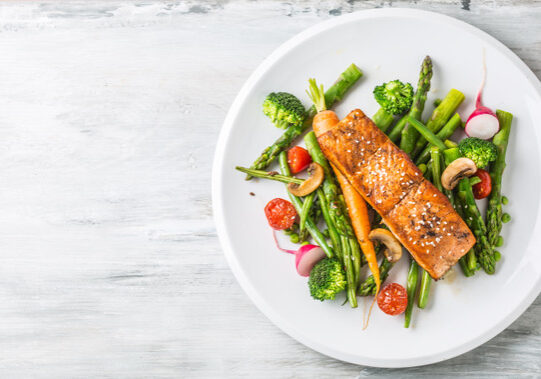 Roasted salmon steak with asparagos broccoli carrot tomatoes radish green beans and peas. Fish meal with fresh vegetable.
